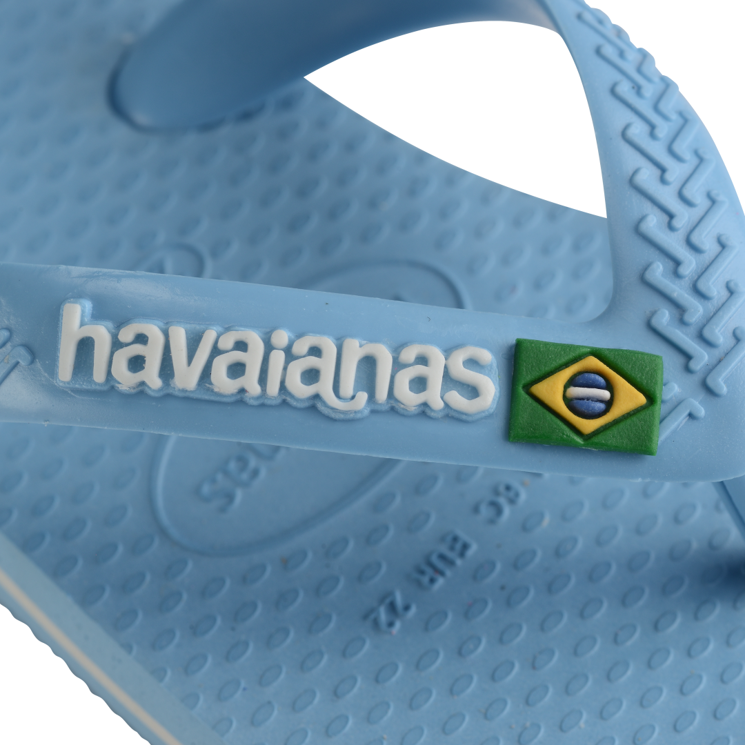 Blue baby flip flop, zoomed in on Havaianas logo and Brazilian flag on strap