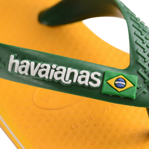 yellow flip flops with green heel straps featuring a brazil flag,zooming in on strap and white havaianas written on the strap with a brazil flag next to it