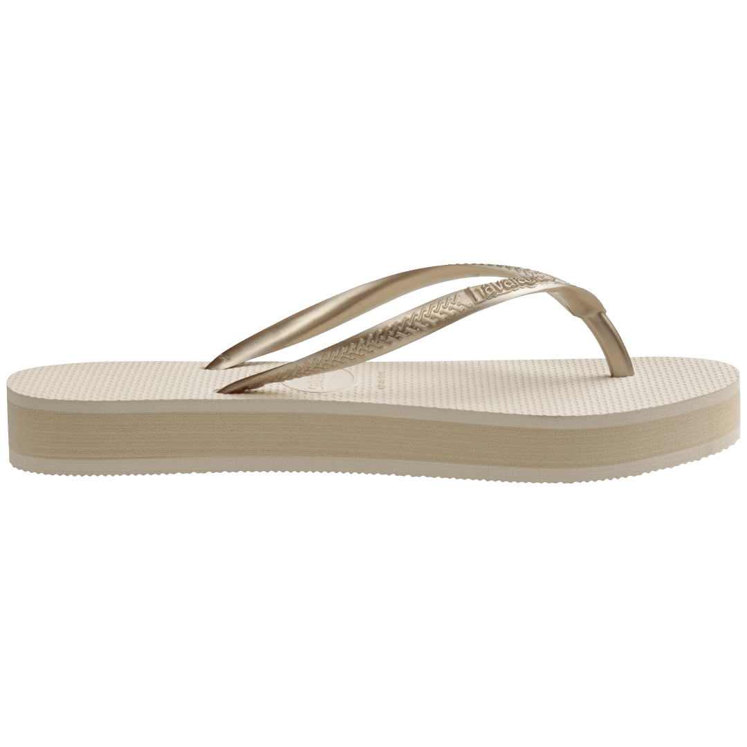 beige platform flip flop, with a darker beige colored midlayer between the sole and bottom of the flip flop, beige metallic straps, side view