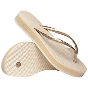 beige platform flip flop, with a darker beige colored midlayer between the sole and bottom of the flip flop, beige metallic straps, one sandal leaning on the other, toe side down