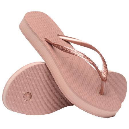 light pink flip flops with a platform and a pink metallic strap, one sandal balancing on the other, toe side down