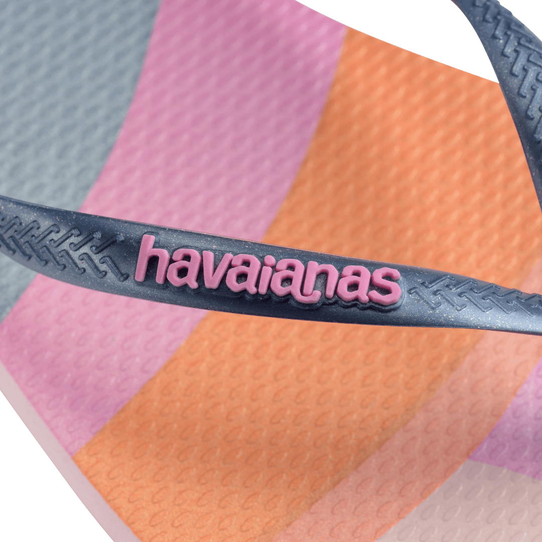 Kid's multicolor abstract print of sunset over the horizon of waves flip flops with navy glitter straps and pink logo detail view