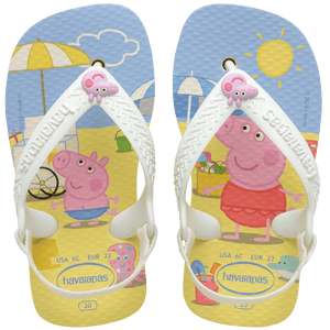 peppa pig on a beach with beach toys and animals, yellow sand and a blue sky, with a peppa pig charm on the white straps, top view