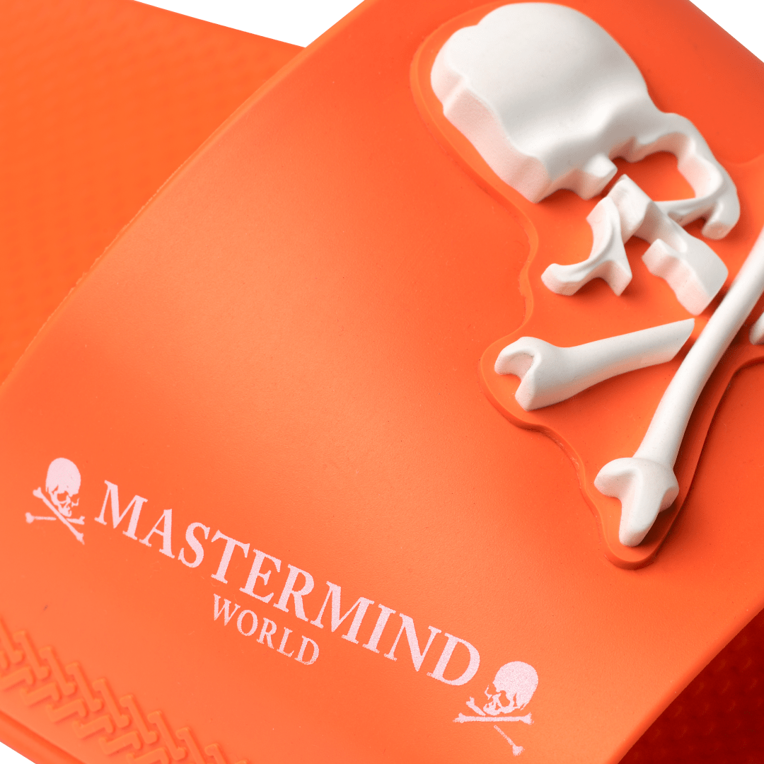 Men's Mastermind orange slides with white skull & cross-bones, logo detail view