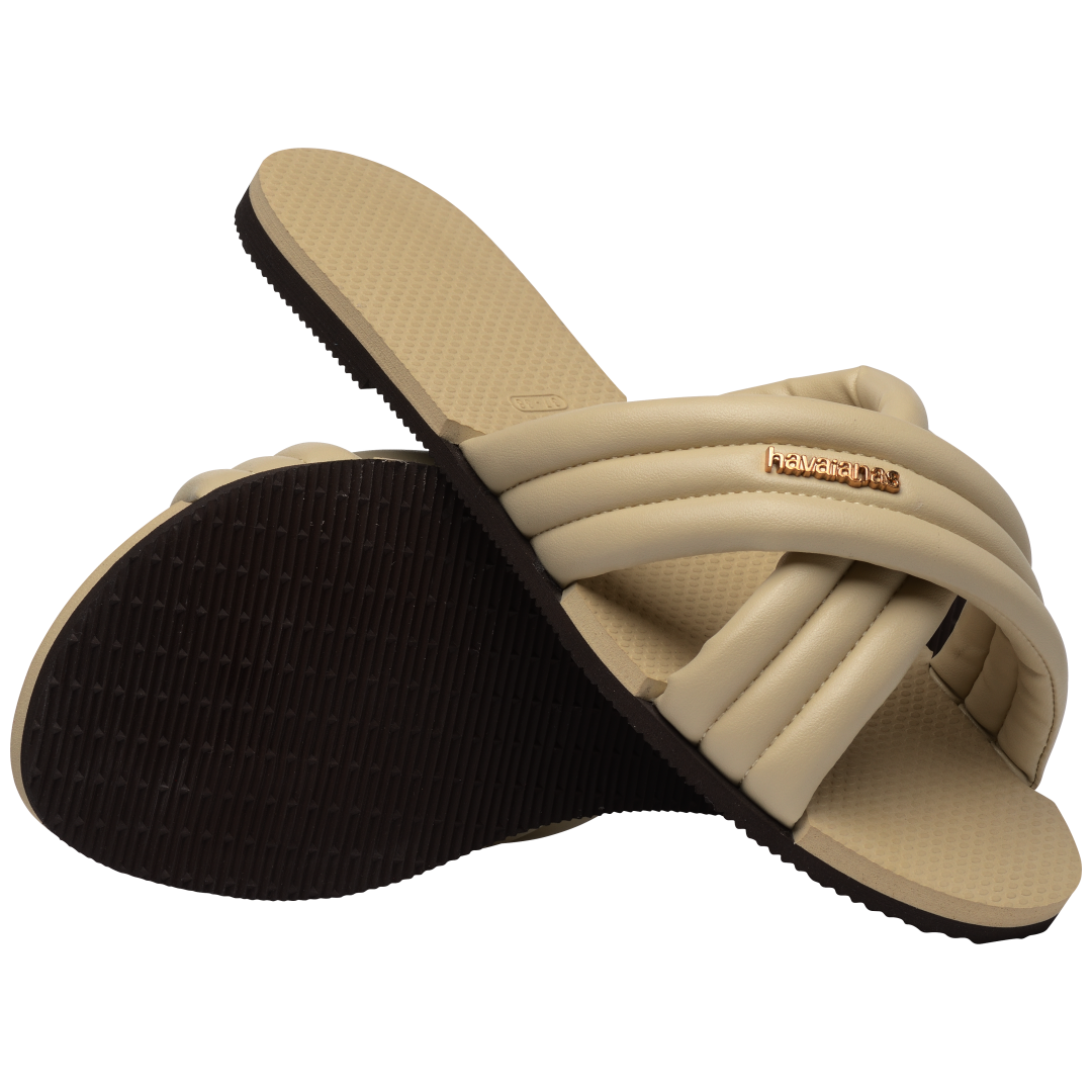 Cream criss-cross strap slide sandal with right shoe perched on left view showing brown sole