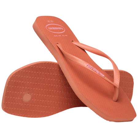 square-toe flip flop in orange color with pink havaianas logo on the strap, one flip flop resting toe side down, on a diagonal, on the other flip flop