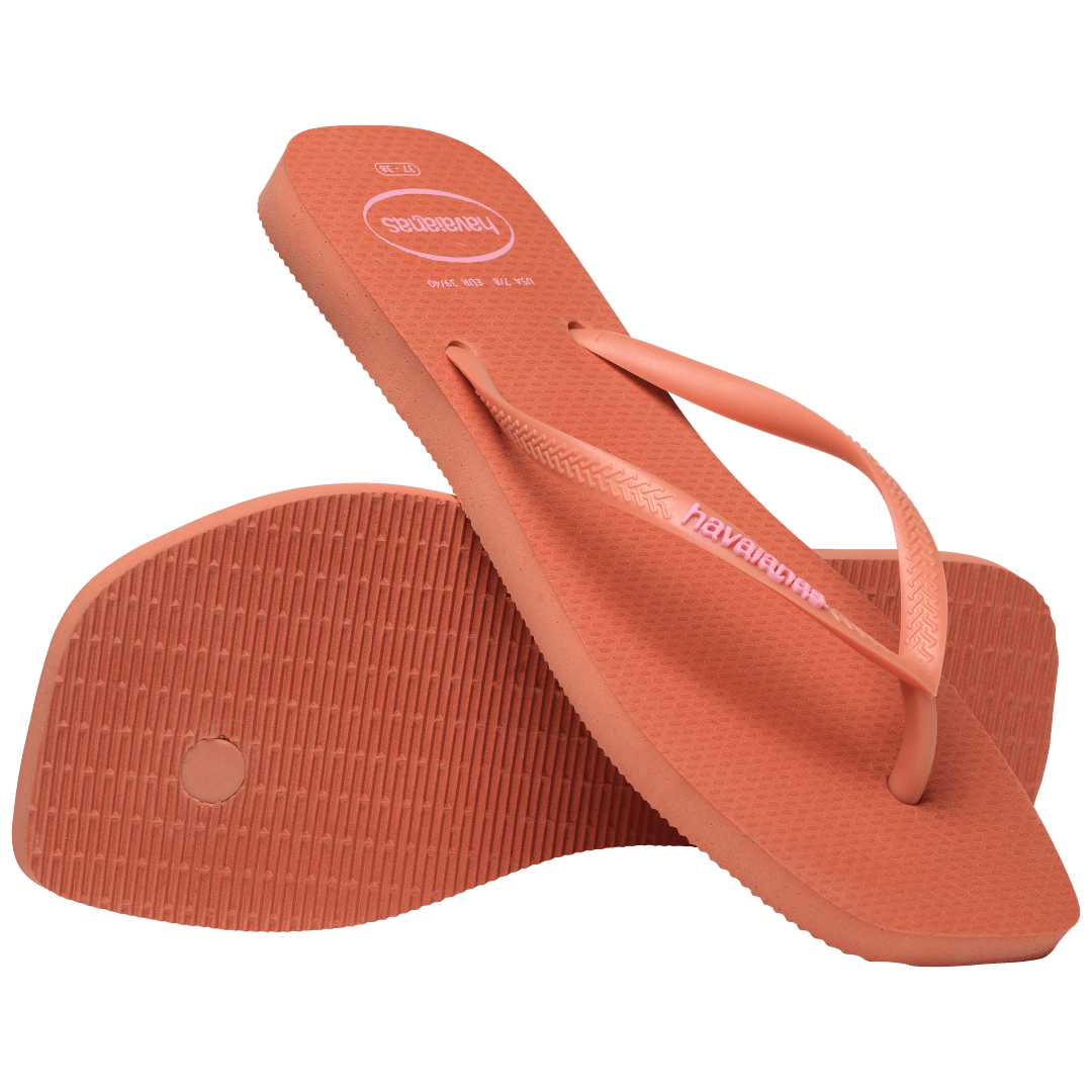 square-toe flip flop in orange color with pink havaianas logo on the strap, one flip flop resting toe side down, on a diagonal, on the other flip flop