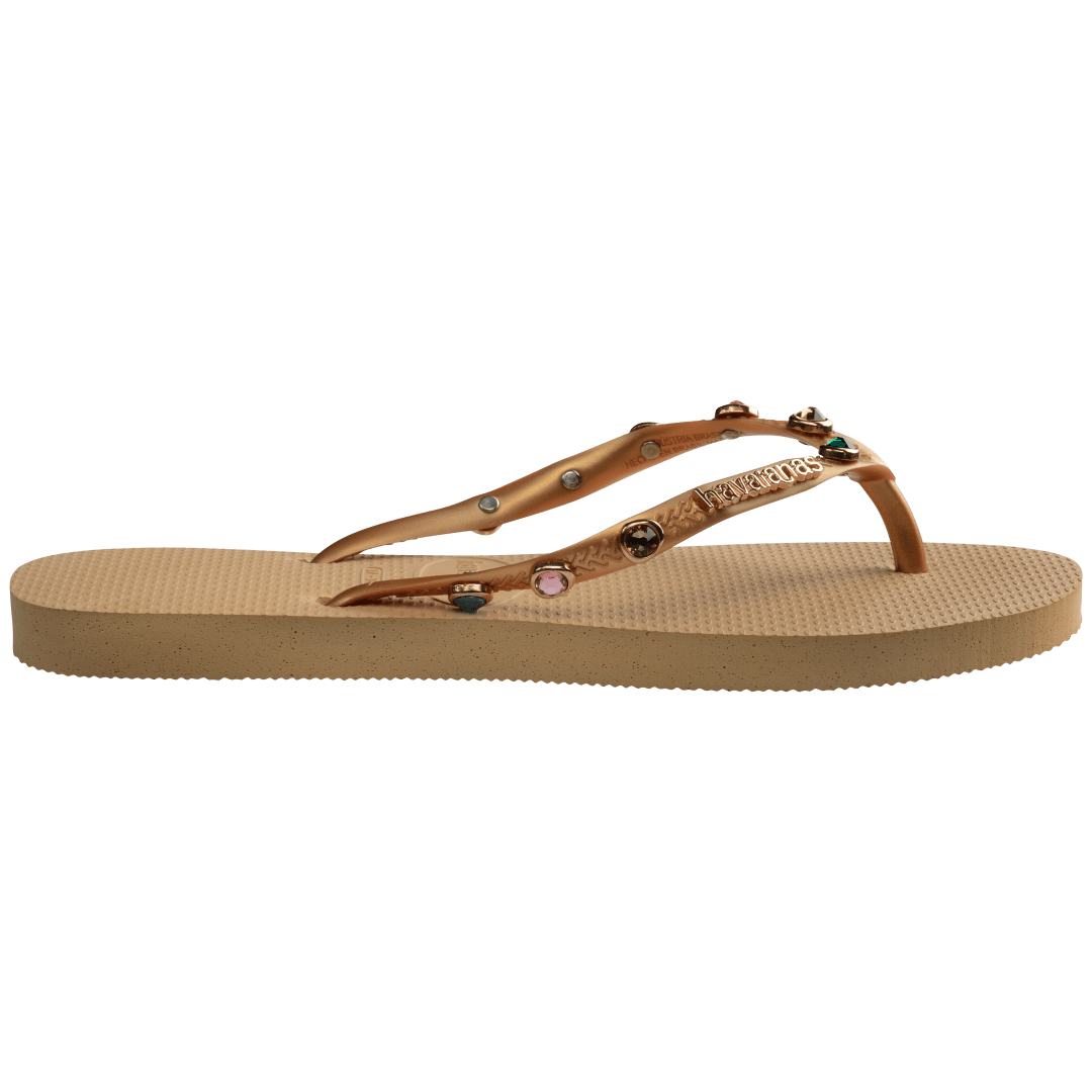 Women's tan flip flops with gold metallic straps featuring multicolor crystals side view