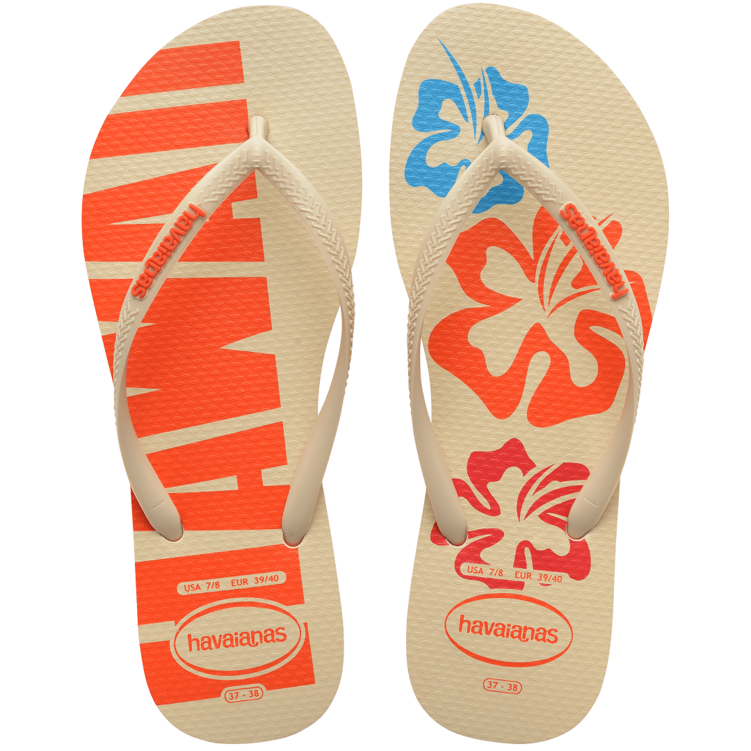 Women's cream flip flop with blue, orange and red flowers and orange printed Hawaii on the left foot top view