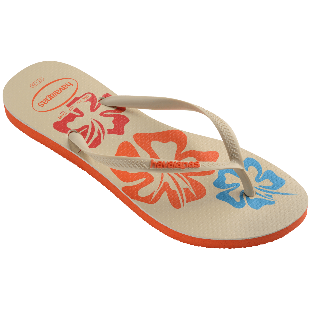 Women's cream flip flop with blue, orange and red flowers and orange printed Hawaii on the left foot 3/4 side view showing orange sole