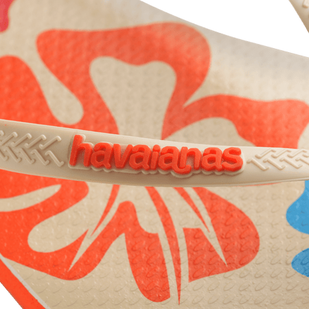 Women's cream flip flop with blue, orange and red flowers and orange printed Hawaii on the left foot detail orange logo view