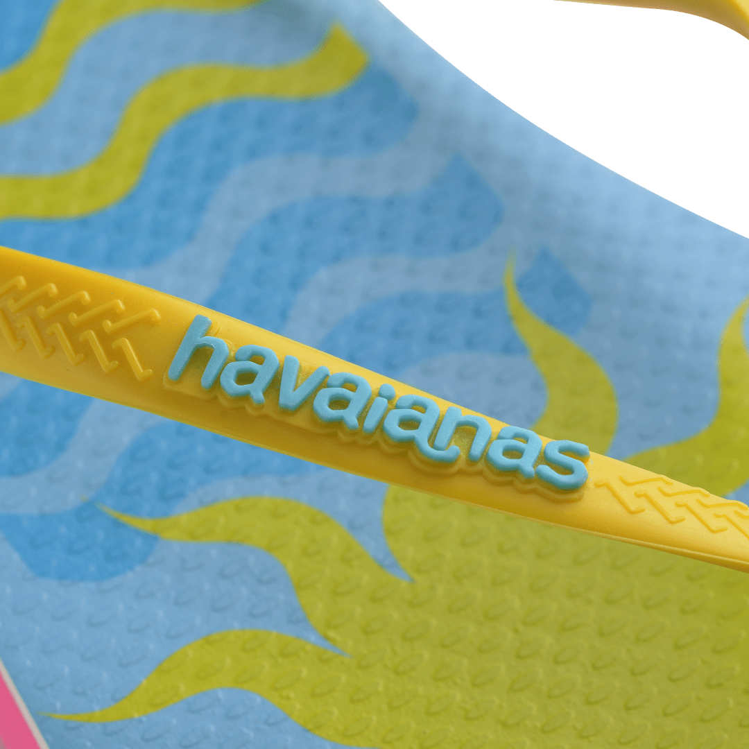 Women's light blue flip flops with yellow straps and pink Miami print on the left foot and yellow sun and blue waves print on the right foot detail strap view