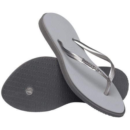 light grey sandals with darker grey outline around footbed, with metallic grey straps and a silver metal havaianas logo on the strap, one shoe leaning on the other toe side down