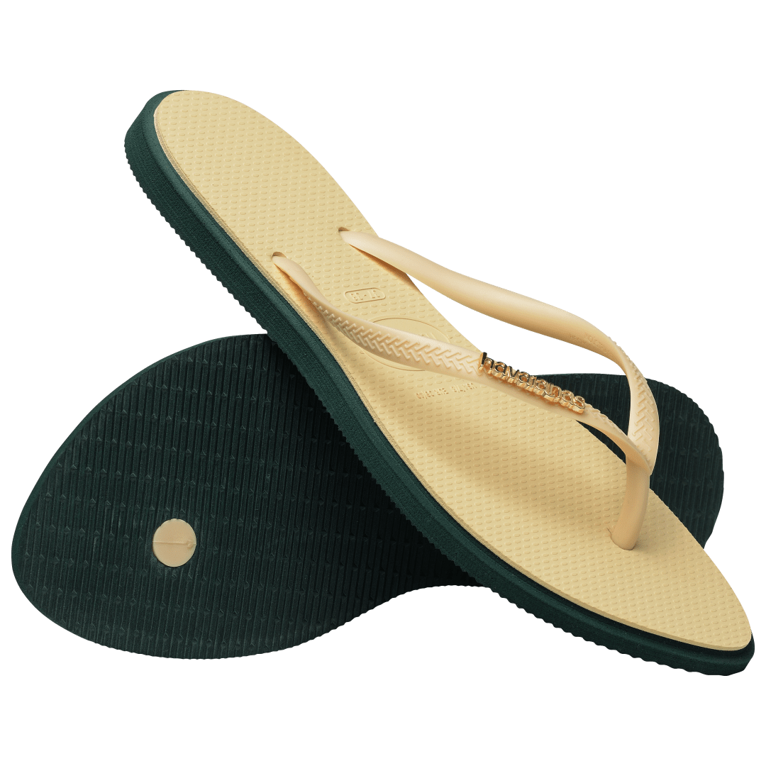 Women's cream pointed toe flip flops with dark green contrast sole, right shoe perched on left