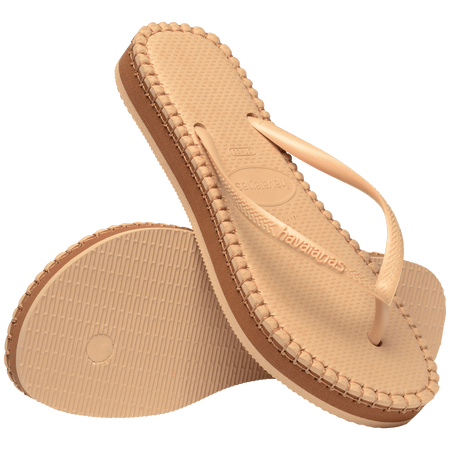 beige sandal with darker brown stitching and a dark brown midlayer between the sole and bottom of shoe, one sandal leaning on the other, toe side down