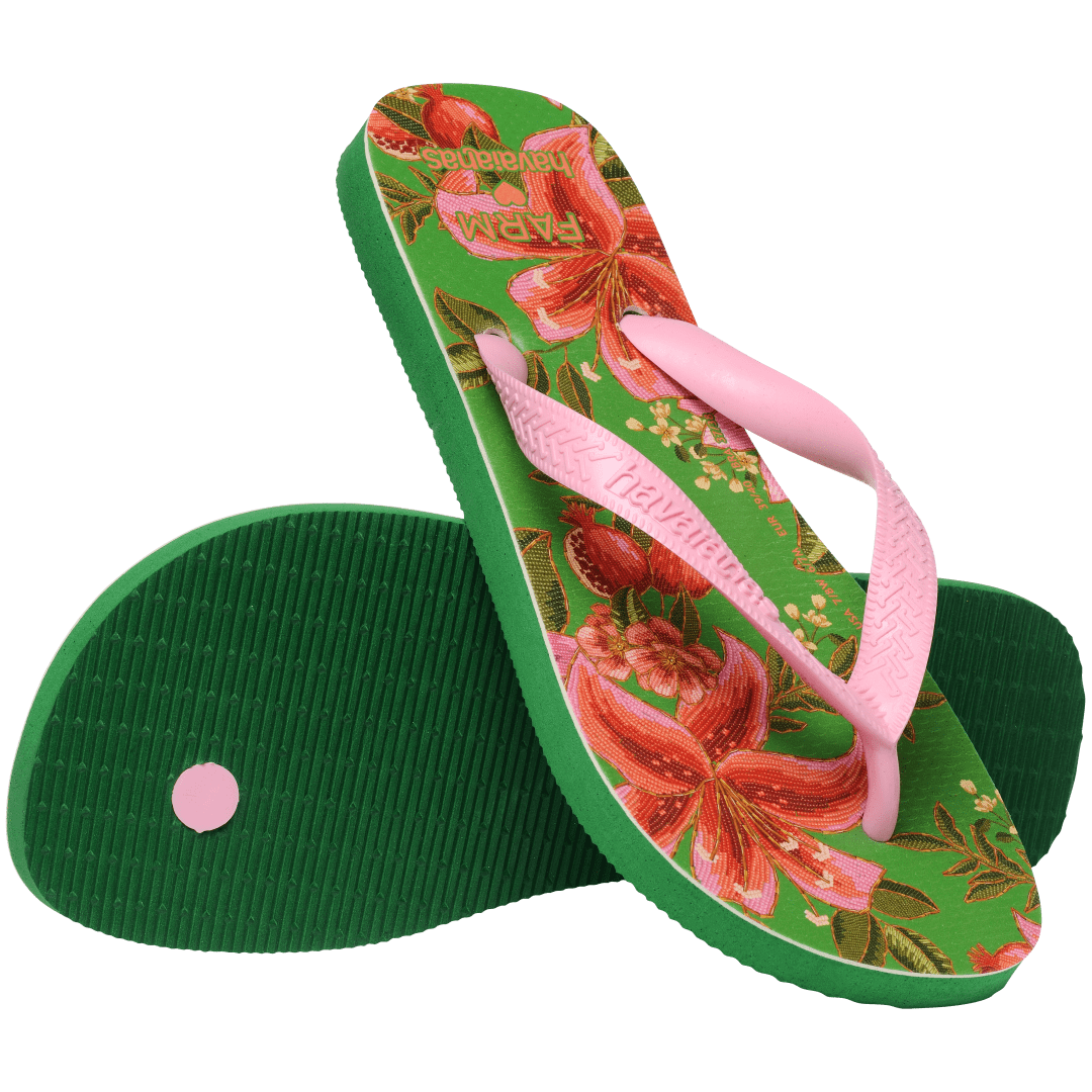 flip flops with green sole featuring pink flowers and pink straps, one flip flop resting on the other on diaganol