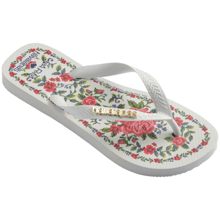 flip flops with pink flowers on a white background with white straps with a gold havaianas logo on them, front-right facing