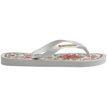 flip flops with pink flowers on a white background with white straps with a gold havaianas logo on them, side facing