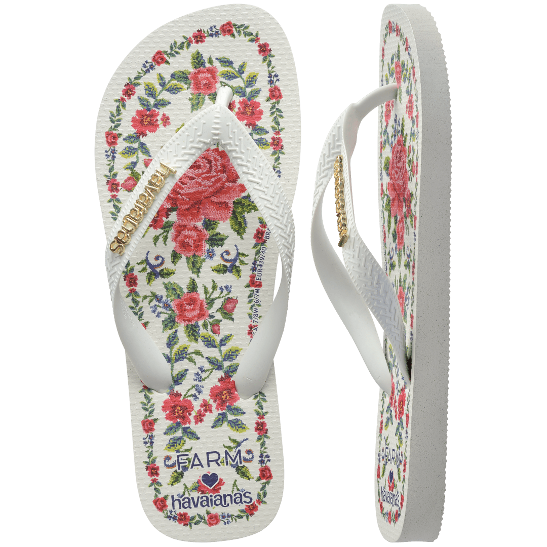 flip flops with pink flowers on a white background with white straps with a gold havaianas logo on them, one top facing and one side facing