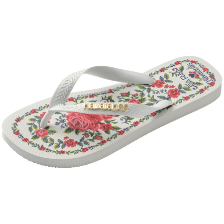 flip flops with pink flowers on a white background with white straps with a gold havaianas logo on them, front-diagonal facing