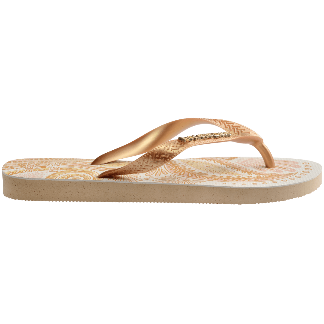 flip flops with gold and light pink abstract print and metallic gold straps with a metal havaianas logo, side facing