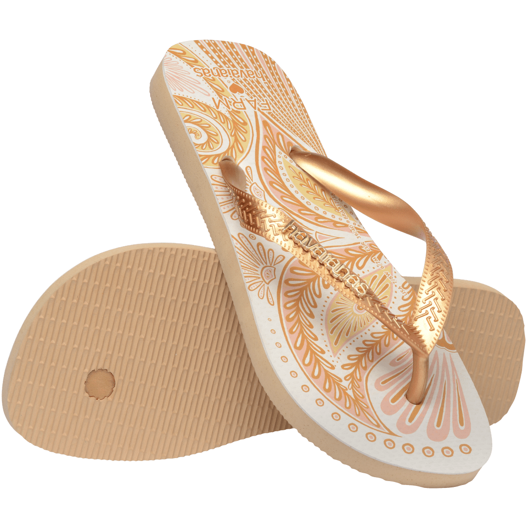 flip flops with gold and light pink abstract print and metallic gold straps with a metal havaianas logo, one flip flop resting on the other flip flop, toe side facing down